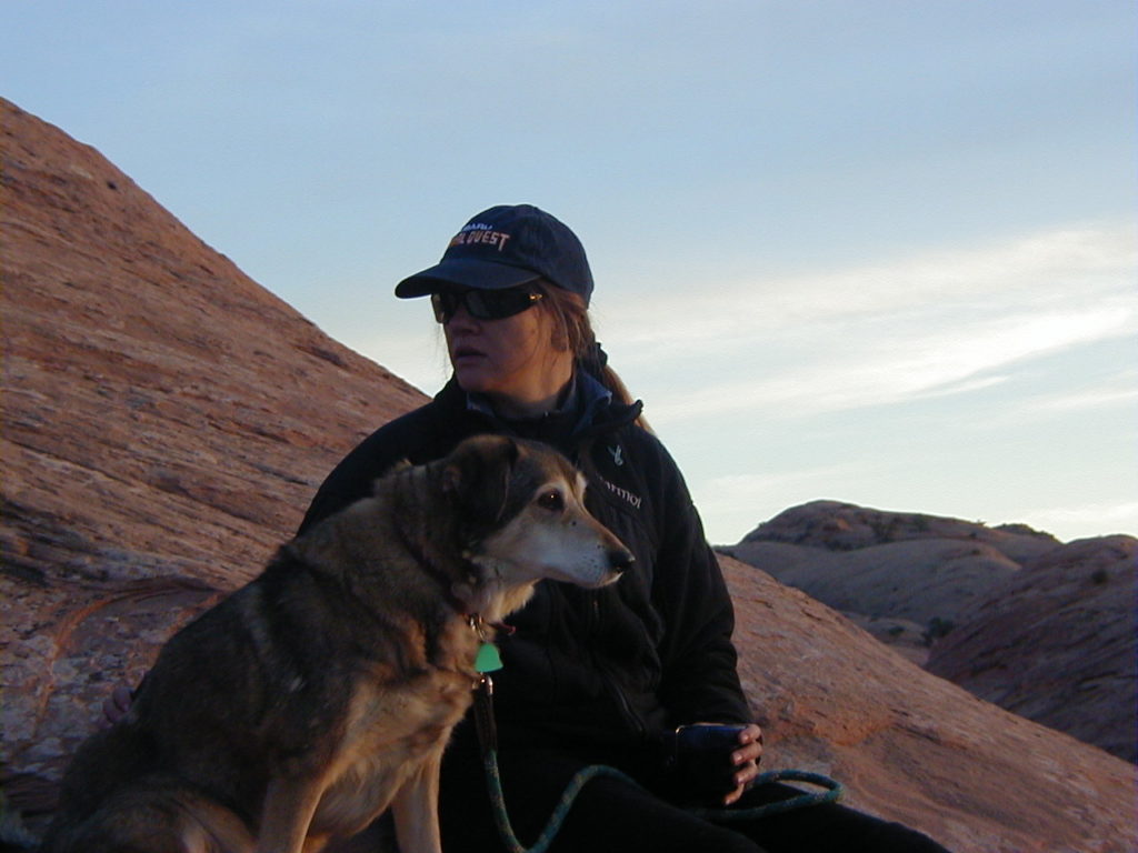 Anna and Tango sitting on Moab rock at sunset